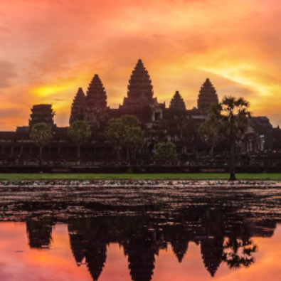 Angkor Wat in Cambodia silhouetted against a colorful sunrise, reflecting on the water