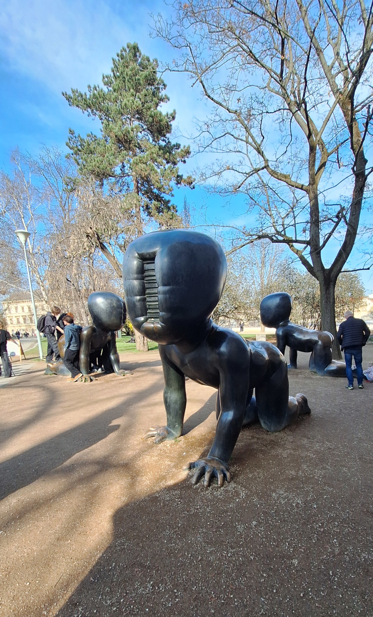 Big baby sculptures by David Černý in Prague with people interacting nearby