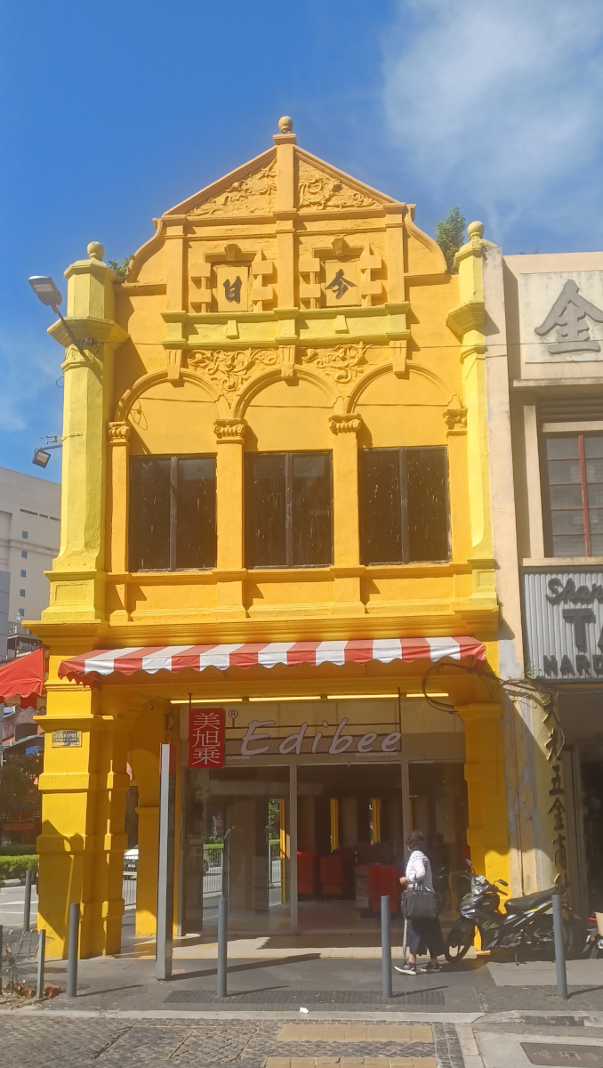Bright yellow colonial-style building in Chinatown against a contrasting blue sky, showcasing the area's diverse architecture