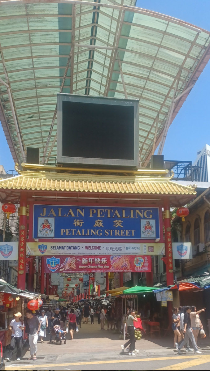 Entrance to Jalan Petaling, Chinatown, featuring a red pagoda design, with visible stall holders inside the bustling Petaling Street Market