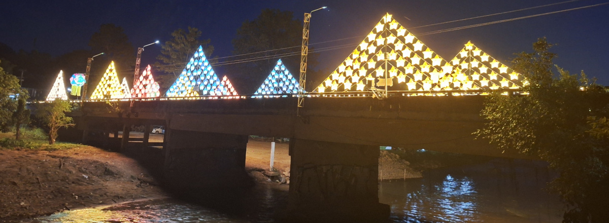 The Pai Bridge illuminated at night, reflecting vibrant lights on the Pai River, creating a picturesque scene in the charming town of Pai.