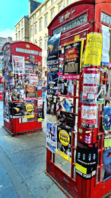 Phone boxes on the Royal Mile covered in colourful Fringe Festival flyers
