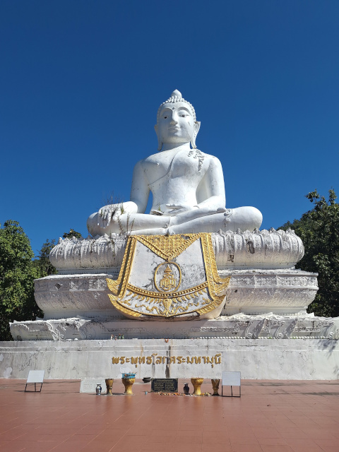 The White Buddha in Pai, North Thailand, towers against a clear blue sky, seen after climbing 353 steps to the iconic site.