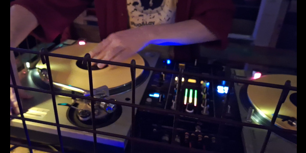 Close-up of DJ hand mixing with yellow vinyl records at a ruin bar in Budapest