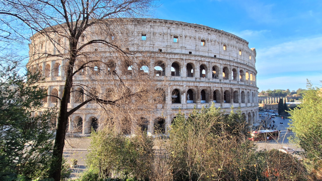 Colosseum View from Park – On the Way from Termini, Rome View of the Colosseum from the park with trees, blue sky, and stunning architecture Title