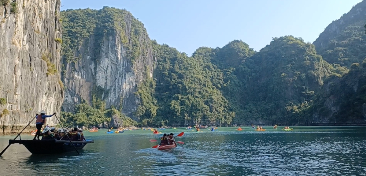 Kayaking in Ha Long Bay with larger passenger boat being paddled by a person