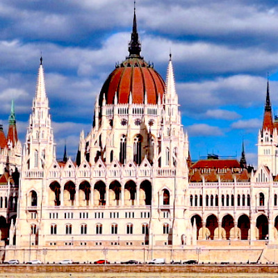 Parliament building in budapest, with a bright blue sky an little white fluffy clouds.