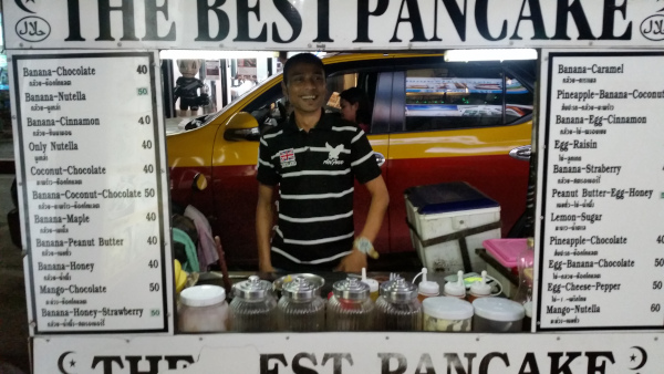 Street Vendor Offering Delicious Banana Pancakes in Koh Phangan Street vendor selling banana pancakes with a variety of delicious fillings and toppings displayed on boards