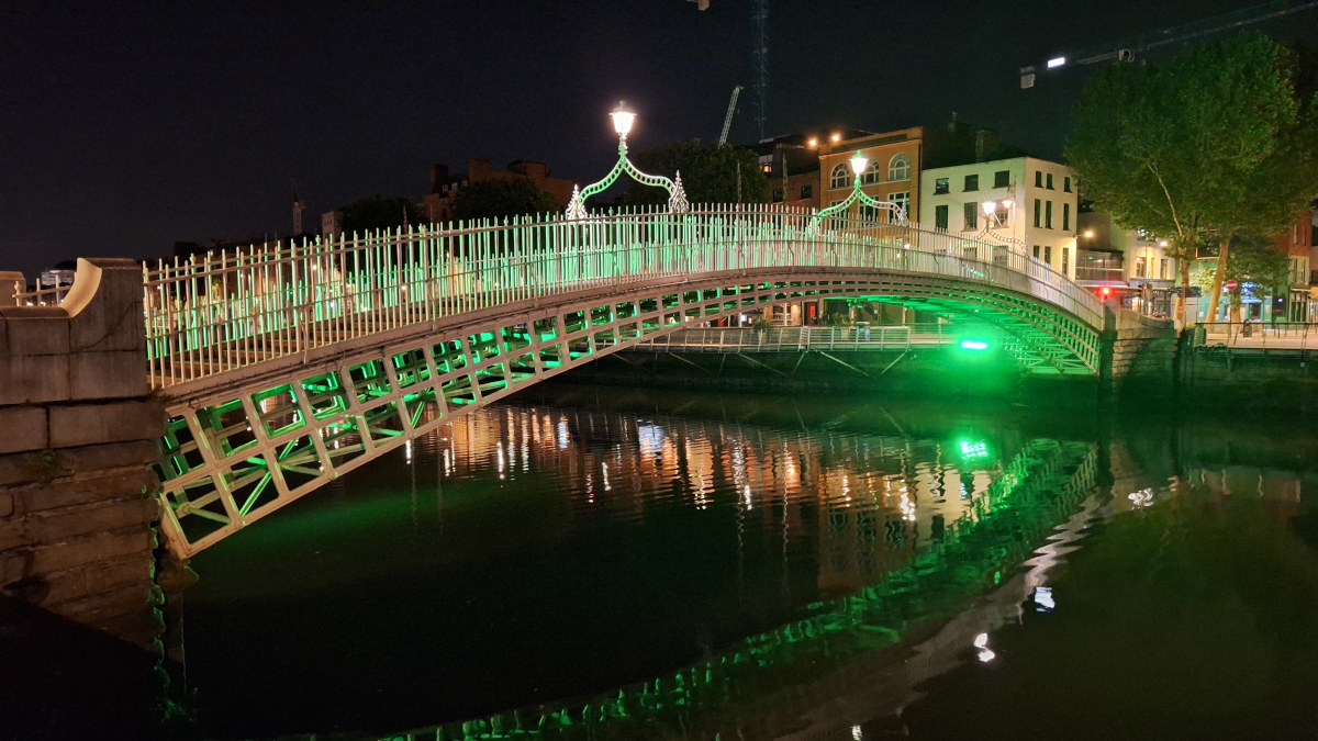 Illuminated Ha’penny Bridge Reflecting in the River Liffey Ha'penny Bridge in Dublin, Ireland, reflected in the River Liffey with green LED lighting at night.