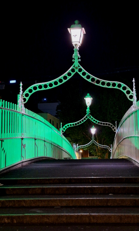Liffey Bridge- Ha’penny Bridge with Green LED Lights Ha'penny Bridge in Dublin illuminated by green LED lights in the evening, highlighting its intricate archways and streetlamps