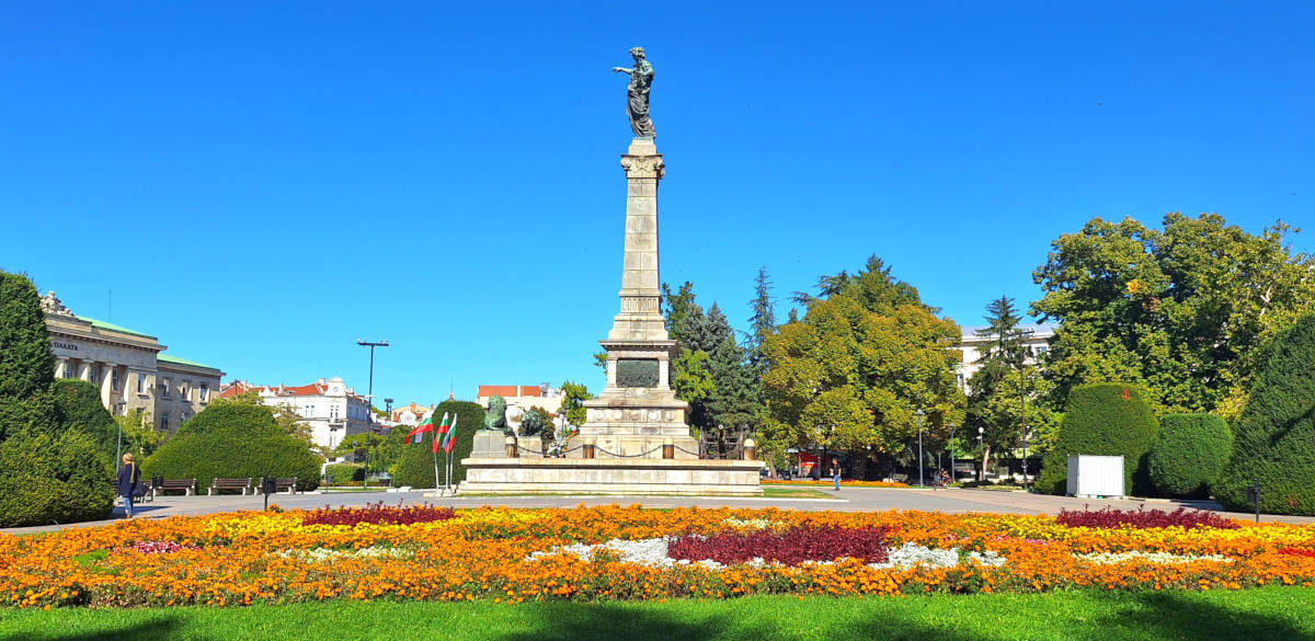 Freedom Monument in Ruse, surrounded by a garden filled with colorful flowers and bedding plants