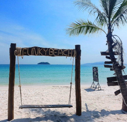 Rope swing with a wooden seat on powdery white sands and blue sky at Funky Beach, Koh Rong