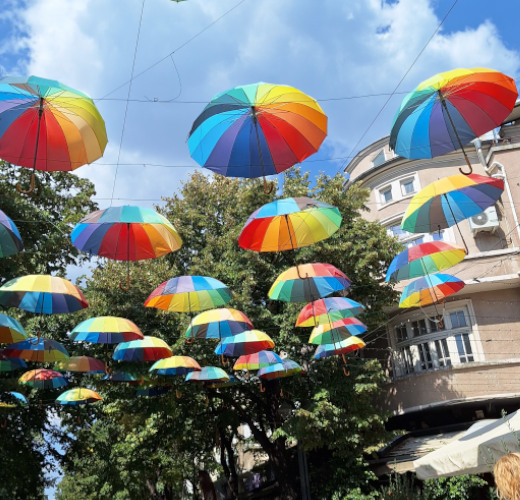 Colourful umbrellas hanging as street art installation in Varna, Bulgaria, against a bright blue sky